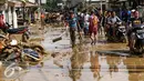 Warga dan pengendara motor melintas di sepanjang jalan yang dipenuhi lumpur di komplek Pondok Gede Permai Jatiasih, Bekasi, Jumat (22/04).Banjir yang telah merendam ratusan rumah warga mengakibatkan air lumpur mengendap. (Liputan6.com/Fery Pradolo)