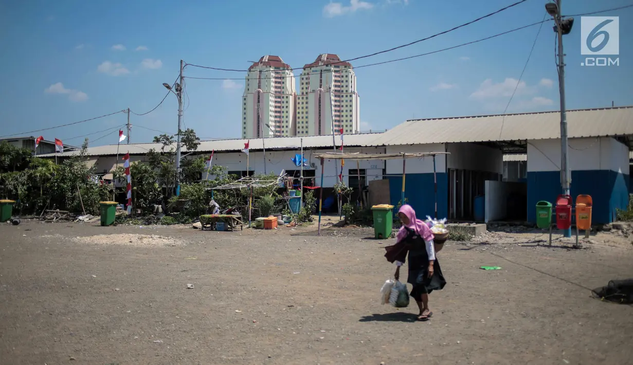 Seorang pedagang melintas dekat "shelter" atau hunian sementara di Kampung Akuarium, Jakarta, Kamis (22/8/2019). Warga Kampung Akuarium berharap Pemprov DKI Jakarta segera menyediakan hunian tetap di kawasan tersebut setelah dua tahun menempati hunian sementara. (Liputan6.com/Faizal Fanani)
