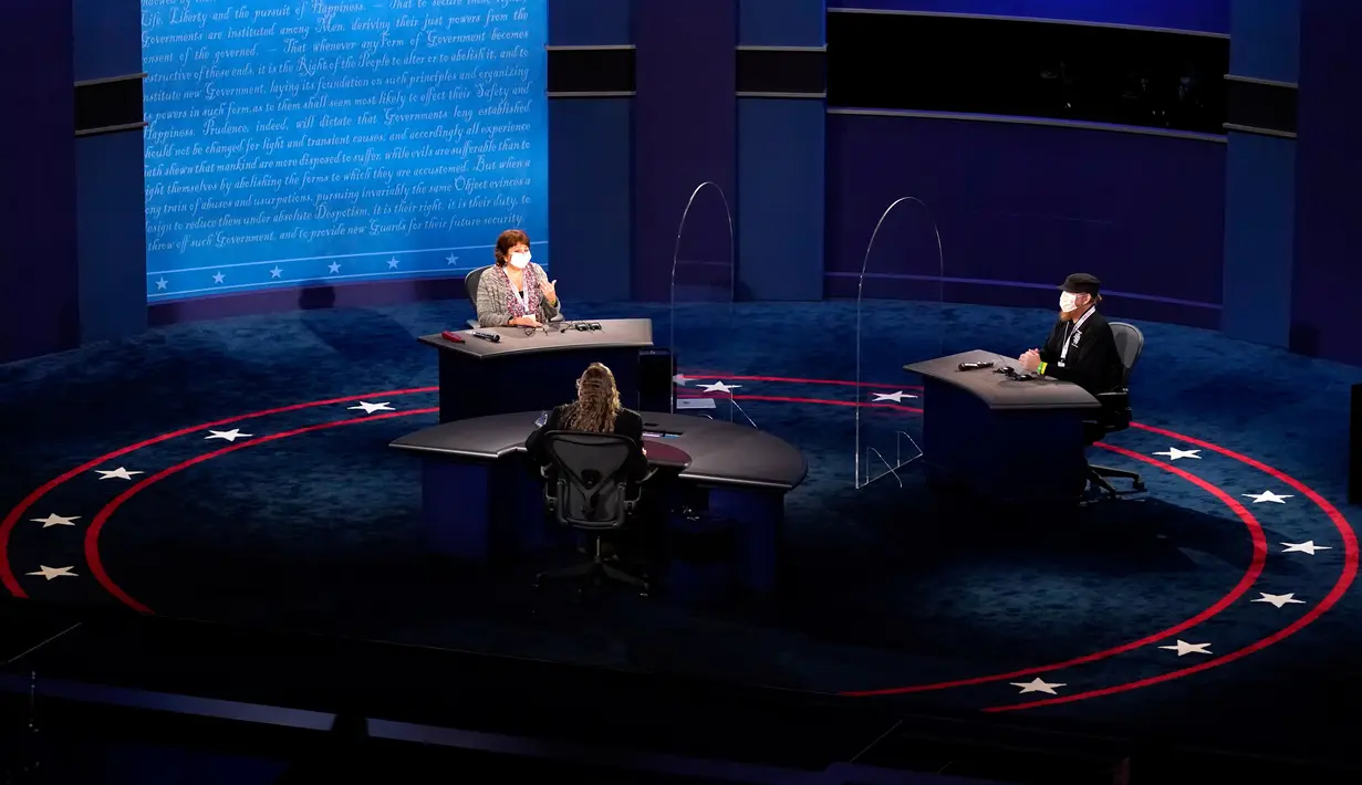 Tim produksi berada di atas panggung di dekat pembatas kaca plexiglass yang akan berfungsi sebagai penghalang untuk mengurangi resiko penyebaran COVID-19 saat persiapan untuk debat calon wakil presiden AS di Universitas Utah, Salt Lake City, Selasa (6/10/2020). (AP Photo/Julio Cortez)