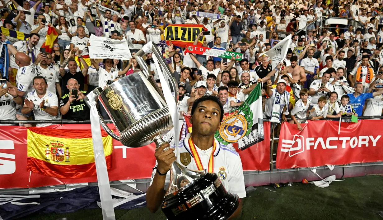 Pemain Real Madrid, Rodrygo, saat mengangkat piala Copa del Rey 2022/2023 dihadapan para penonton setelah berhasil mengalahkan Osasuna 2-1 dalam partai final di La Cartuja, Minggu (7/5/2023). Berkat dua golnya ke gawangOsasuna, Real Madrid berhasil mendapatkan gelar Copa del Rey ke-20. (AFP/Javier Soriano)