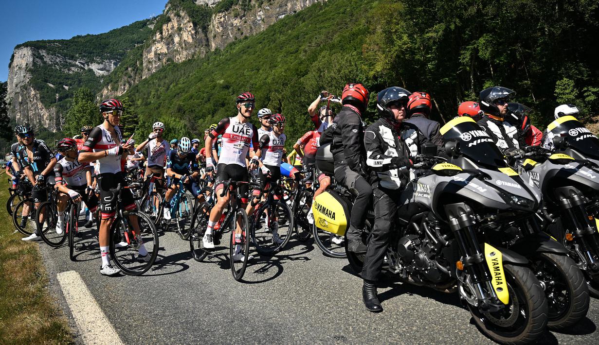 Rombongan pebalap dihentikan semenatara oleh regulator balapan karena terjadi demonstrasi perubahan iklim yang menutup rute balapan pada etape ke-10 Tour de France, antara Morzine dan Megeve, di Pegunungan Alpen Prancis, pada 12 Juli 2022. (AFP/Marco Bertorello)