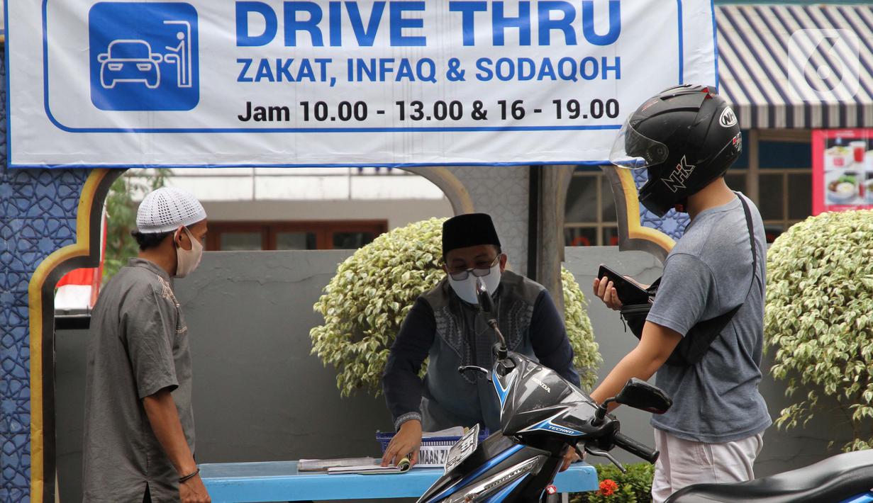 Petugas Amil Zakat melayani warga yang membayar zakat fitrah melalui sistem "drive thru" di Masjid Nurul Hidayah, Tanah Kusir, Jakarta, Selasa (19/5/2020). Layanan zakat "drive thru" selama pandemi COVID-19 ini diberlakukan dengan protokol kesehatan dan keselamatan. (Liputan6.com/ Johan Tallo)