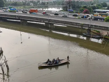 Pengendara sepeda motor menggunakan jasa perahu eretan menyeberangi Sungai Kali Angke di Kecamatan Penjaringan, Jakarta, Rabu (29/5/2024). (merdeka.com/Arie Basuki)