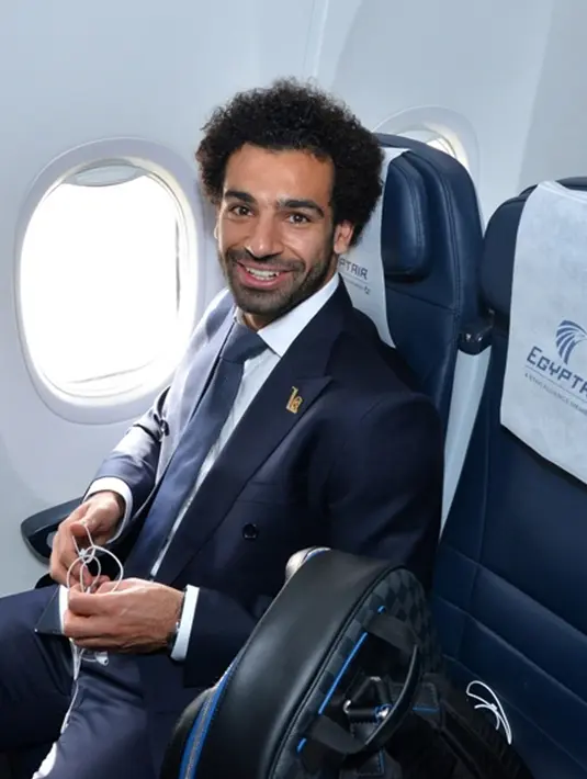 Penyerang Timnas Mesir, Mohamed Salah tersenyum saat berada di pesawat di Kairo (10/6). Pemain Liverpool ini masih dalam masa pemulihan cedera bahu yang dideritanya pada final Liga Champions melawan Real Madrid. (AFP Photo/Karim Jaafar)