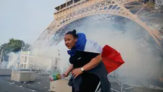 Seorang demonstran berlari menghindari gas air mata yang ditembakan polisi di bawah Menara Eiffel di dekat zona penggemar Paris sebelum laga Portugal vs Prancis di Final EURO 2016 di Prancis (10/6). (REUTERS/Stephane Mahe)