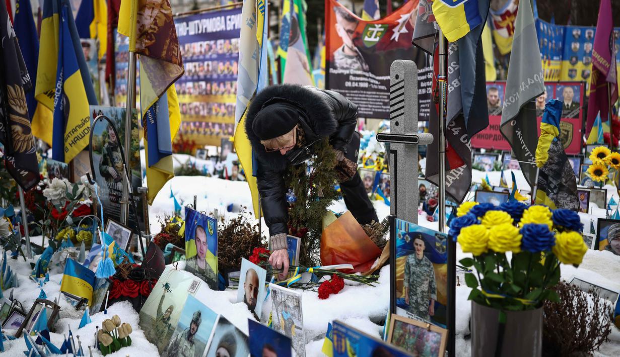 Dalam laporan terbarunya, Center for Strategic and International Studies (CSIS) memperkirakan, sekitar 1,8 juta tentara dari kedua belah pihak tewas, terluka, atau hilang sejak invasi skala penuh pada 24 Februari 2022. Tampak dalam foto, seorang warga setempat mengunjungi tugu peringatan sementara untuk tentara Ukraina dan asing di Lapangan Kemerdekaan, Kyiv, saat peringatan keempat invasi Rusia ke Ukraina, Selasa 24 Februari 2026. (HENRY NICHOLLS/AFP)