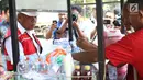Menteri PUPR, Basuki Hadimuljono membeli kopi yang dijajakan pedagang seusai meninjau renovasi stadion di Gelora Bung Karno (GBK), Jakarta, Kamis (10/5). Basuki meninjau kesiapan fasilitas dan prasarana untuk Asian Games 2018. (Liputan6.com/Angga Yuniar)