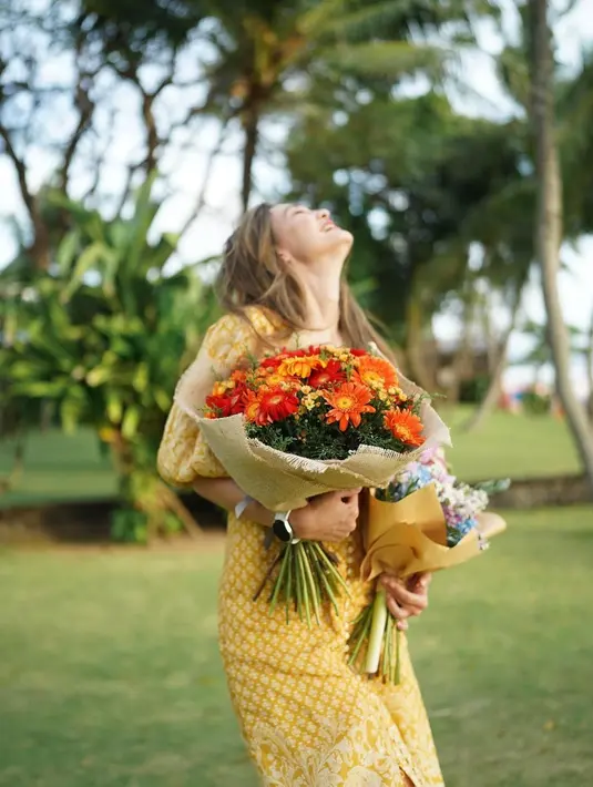Sambil membawa buket bunga, penggemar RM BTS ini pun terlihat mengenakan long dress warna kuning yang membuat Luna Maya lebih memancarkan aura bahagiannya. (Instagram/lunamaya)