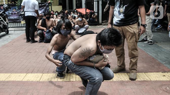 Massa pelajar dan remaja berjalan jongkok saat digiring ke mobil tahanan menuju Polda Metro Jaya di Polsek Subsektor Palmerah, Jakarta, Kamis (8/10/2020). Mereka diringkus polisi saat hendak menuju gedung DPR untuk mengikuti unjuk rasa bersama buruh dan mahasiswa. (merdeka.com/Iqbal Nugroho)