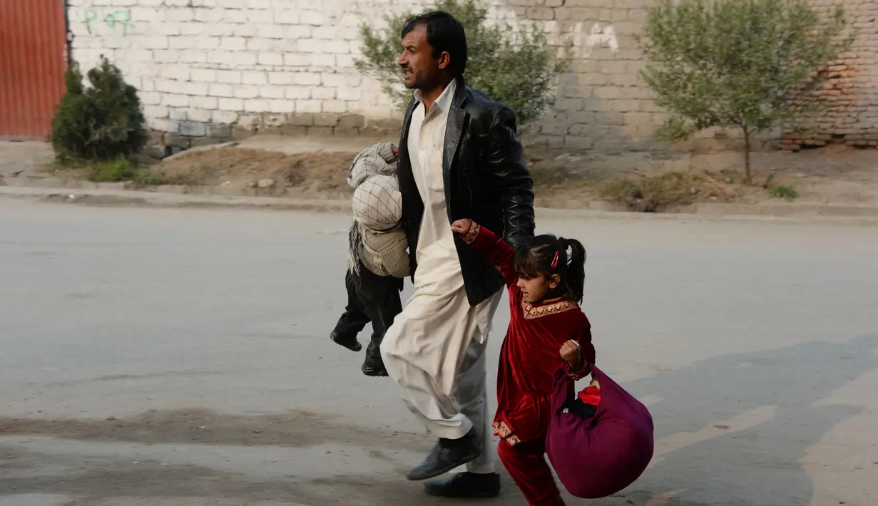 Seorang pria membawa kedua anaknya untuk menyalmatkan diri saat terjadi serangan di dekat kantor amal Inggris Save the Children di Jalalabad, Afghanistan (24/1). (AFP Photo/Noorullah Shirzada)