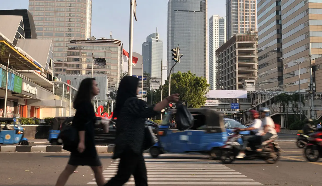 Pejalan kaki melintasi coretan yang dibuat buruh di zebra cross kawasan Sarinah, Jakarta, Selasa (1/5). Jejak vandalisme tersebut antara lain coretan berisi kata-kata kritis buruh dan poster di berbagai fasilitas umum. (Merdeka.com/ Iqbal S. Nugroho)