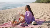 Mengikuti tren masa kini, Jessica Mila pun menggelar kain untuk piknik di pantai. Di momen pikniknya kali ini, ia nampak mengenakan jumpsuit warna ungu lilac dan mengenakan riasan natural. (Liputan6.com/IG/jscmila)