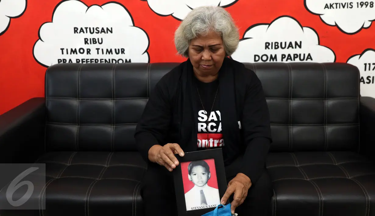 Maria Sanu, keluarga korban kerusuhan Mei 98 memasukkan foto anaknya usai memberi keterangan di kantor KontraS, Jakarta, Kamis (8/12). Mereka menagih komitmen pemerintah segera memenuhi hak-hak korban pelanggaran HAM. (Liputan6.com/Helmi Fithriansyah)