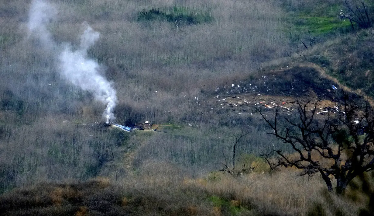 Asap mengepul dari helikopter yang ditumpangi pebasket NBA Kobe Bryant di sisi bukit di Calabasas, California (26/1/2020). Kecelakaan helikopter di Calabasas, California, menewaskan legenda NBA Kobe Bryant, Minggu 26 Januari waktu setempat. (AP Photo/Richard Vogel)