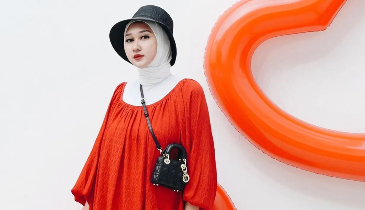 Menggunakan simple dress berwarna oranye, Dian Pelangi memilih memadukannya dengan turtle neck dan hijab putih. Ia juga menggunakan topi berwarna hitam senada dengan sling bag mininya. (Liputan6.com/IG/@dianpelangi)