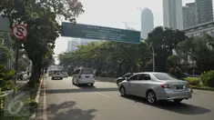 Kendaraan melaju di bawah papan petunjuk penerapan sistem ganjil genap di Bundaran Senayan, Jakarta, Rabu (27/7). Kebijakan pembatasan kendaraan dengan penerapan pelat ganjil genap dimulai hari ini hingga tanggal 26 Agustus. (Liputan6.com/Gempur M Surya)