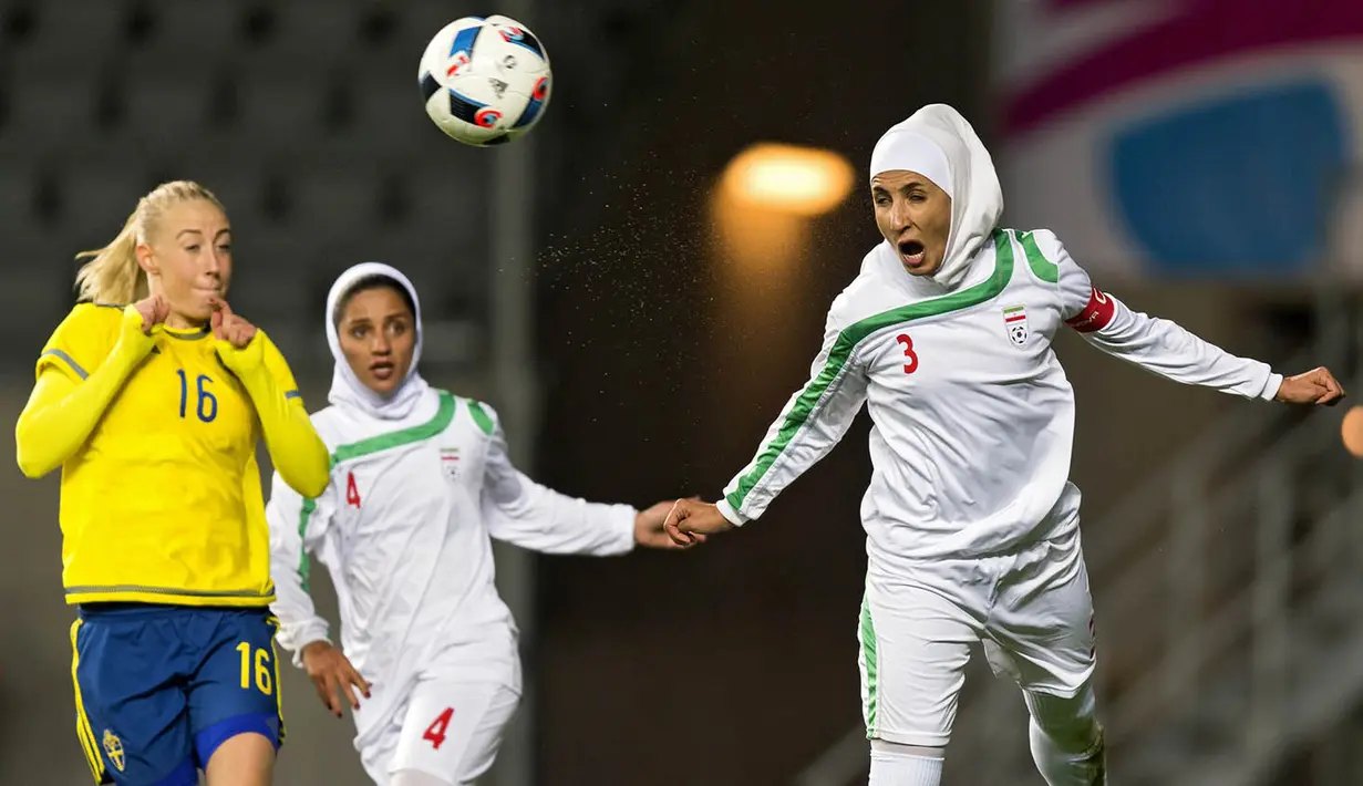 Foto Olahraga Terbaik - Pesepak bola Iran, Koyestan Khosravi, membuang bola dari kejaran pemain Swedia, Petra Andersson,  pada laga persahabatan sepak bola putri di Gothenburg, Swedia, Jumat (21/10/2016). (EPA/Thomas Johansson)