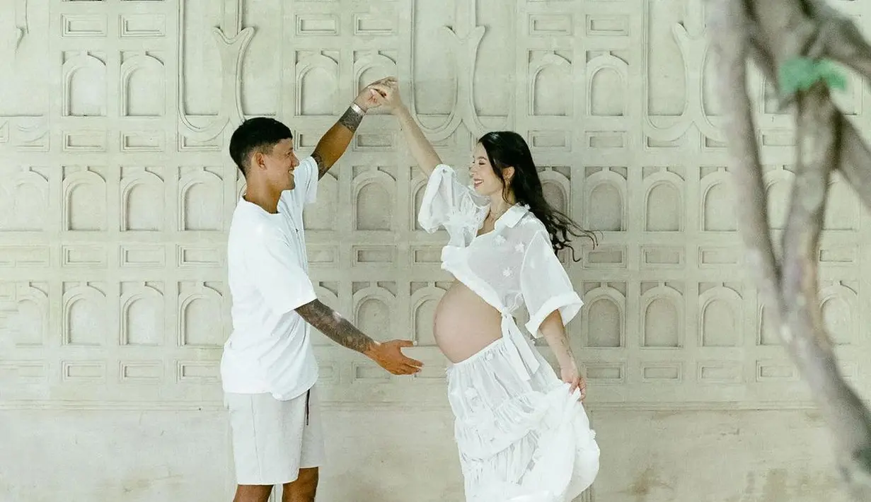 Putih merupakan pilihan warna yang tak pernah salah, seperti terlihat dari foto pasangan Jennifer dan Irfan Bachdim ini. Irfan memilih gaya kasual yang sederhana, kaus putih polos dengan celana pendek, sedangkan Jennifer memamerkan baby bumpnya dengan atasan putih lengan pendek dengan rok panjang yang flowy. Foto: Instagram.