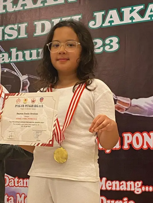 Putri kedua Baim dan Artika memegang piagam dan medali perunggu yang baru saja didapatkan. Zoe mendapatkan di kelas FOIL untuk usia 10 tahun putri. [Instagram/baimguitar]