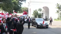 Pegawai Istana mengibarkan bendera merah putih saat rombongan mobil Presiden terpilih Joko Widodo (Jokowi)  melintas menuju gedung DPR di Istana Kepresidenan, Jakarta, Minggu (20/10/2019). Jokowi-Ma'ruf Amin kembali dilantik sebagai Presiden-Wapres RI periode 2019-2024. (Liputan6.com/Angga Yuniar)