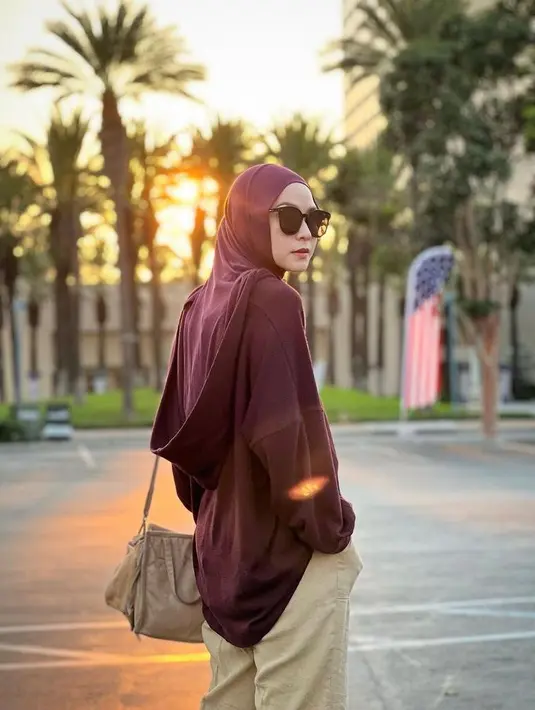 Seperti potret ini, berpose dengan latar matahari terbenam, Zaskia tampil casual chic mengenakan long sleeve top maroon dipadukan dengan hijab warna senada dan cargo pants warna krem. (Instagram/zaskiadyamecca).