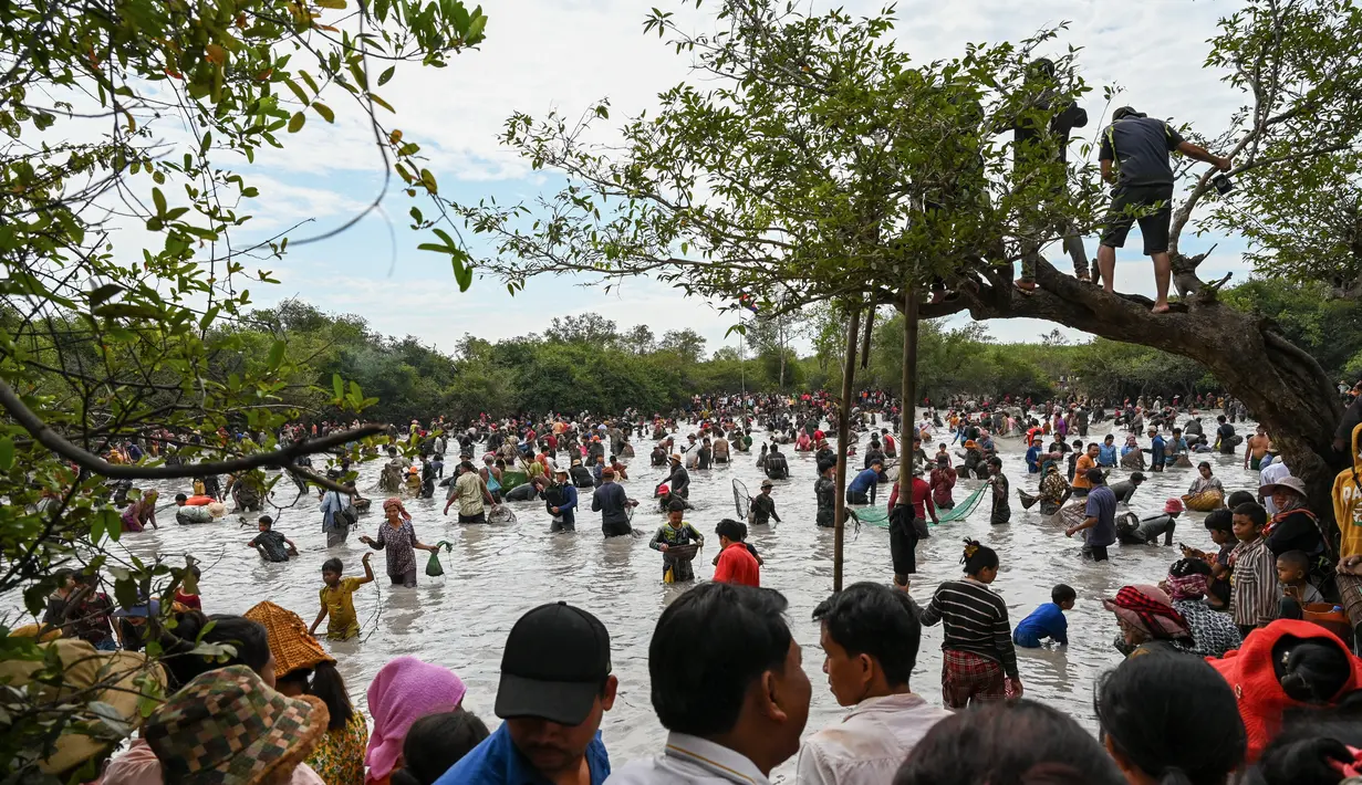 Penduduk desa menangkap ikan selama upacara penangkapan ikan tahunan di komune Choam Krovean di provinsi Tboung Khmum pada 18 Februari 2023. Dengan menggunakan keranjang bambu buatan tangan dan jaring nilon, ratusan orang mengarungi danau berlumpur setinggi paha di Kamboja timur pada hari Sabtu untuk upacara penangkapan ikan tahunan, di mana hanya alat-alat tradisional yang digunakan. (AFP/Tang Chhin Sotthy)