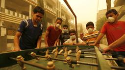 Sejumlah anak mengenakan masker sambil bermain bola meja di Provinsi Homs, Suriah, Senin  (7/8/2015).  Badai ini membuat sebagian rumah sakit menghentikan kegiatannya.  (REUTERS/Omar Sanadiki)