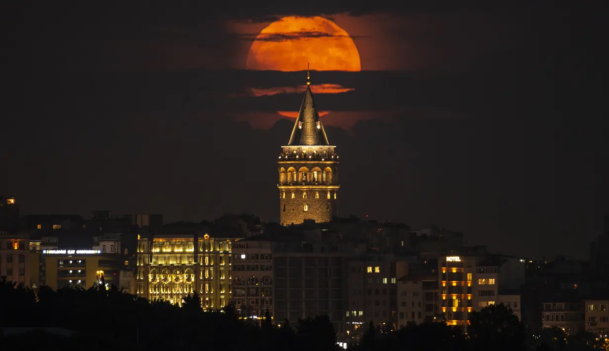 Bulan purnama muncul di belakang Menara Galata, Istanbul, Turki, 14 Juni 2022. Fenomena ini disebut juga sebagai Strawberry Supermoon karena terjadi pada saat panen strawberry. (AP Photo/Emrah Gurel)