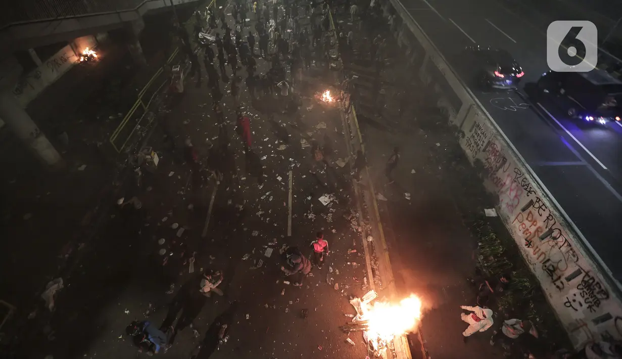 Mahasiswa dan elemen buruh bertahan hingga malam saat aksi di depan Gedung DPR/MPR/DPD, Jakarta, Kamis (16/7/2020). Dalam aksinya, mereka menolak pengesahan RUU Cipta Kerja atau Omnibus Law yang saat ini sedang dibahas DPR bersama pemerintah. (Liputan6.com/Johan Tallo)