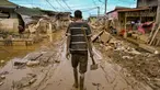 Seorang pria berjalan membawa cangkul di jalanan yang masih berlumpur setelah banjir bandang melanda daerah tersebut di Aceh Tamiang, Provinsi Aceh, pada Sabtu 6 Desember 2025. Gelombang penyakit ancam korban banjir Sumatra di Kabupaten Aceh Tamiang, Provinsi Aceh. (YT HARIONO/AFP)