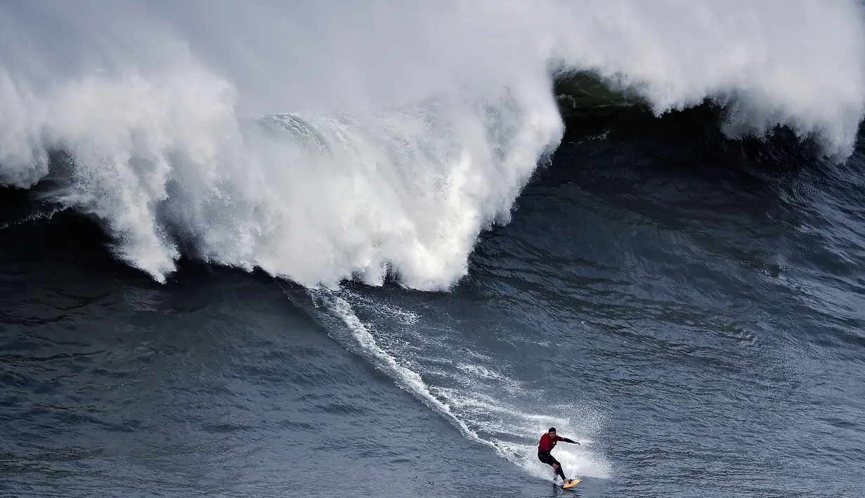 Peselancar asal Chili, Rafael Tapia beraksi saat ombak besar mengejarnya di Praia do Norte di Nazare, Portugal (19/11). Olahraga ini dilakukan dengan menggunakan sebuah papan sebagai alat untuk bermanuver di atas ombak. (AFP/Patricia De Melo Moreira)
