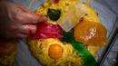 Seorang tukang roti meletakkan buah-buahan mengkristal di atas Bolo Rei atau Kue Raja yang siap untuk dioven di toko roti Padaria da Ne, Amadora, Portugal, 16 Desember 2022. Kue berbentuk cincin ini adalah salah satu sajian khas Natal di Portugal. (CARLOS COSTA/AFP)