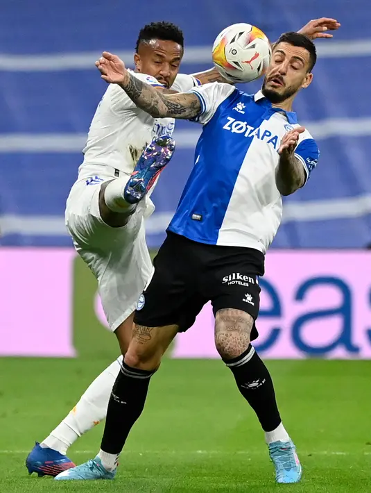 Bek Real Madrid Eder Militao (kiri) berebut bola dengan penyerang Deportivo Alaves Joselu pada pekan ke-25 La Liga Spanyol di Santiago Bernabeu, Minggu (20/2/2022) dinihari WIB. Real Madrid menang meyakinkan dengan skor 3-0. (OSCAR DEL POZO / AFP)