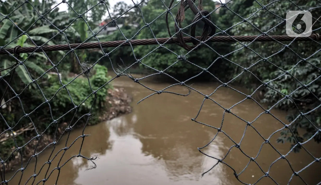 Kondisi jembatan gantung yang sudah tidak layak di kawasan Srengseng Sawah, Jakarta, Sabtu (12/6/2021). Kondisi jembatan gantung yang menjadi akses warga dari Cimanggis menuju Srengseng Sawah atau sebaliknya tersebut beralaskan bambu serta seng. (merdeka.com/Iqbal S. Nugroho)