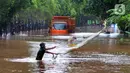 Warga menjala ikan di tengah jalan yang tertutup banjir di kawasan TB Simatupang, Jakarta Selatan, Sabtu (20/2/2021). Banjir terjadi akibat luapan Kali Serua yang berada di pinggir jalan tol. (merdeka.com/Arie Basuki)