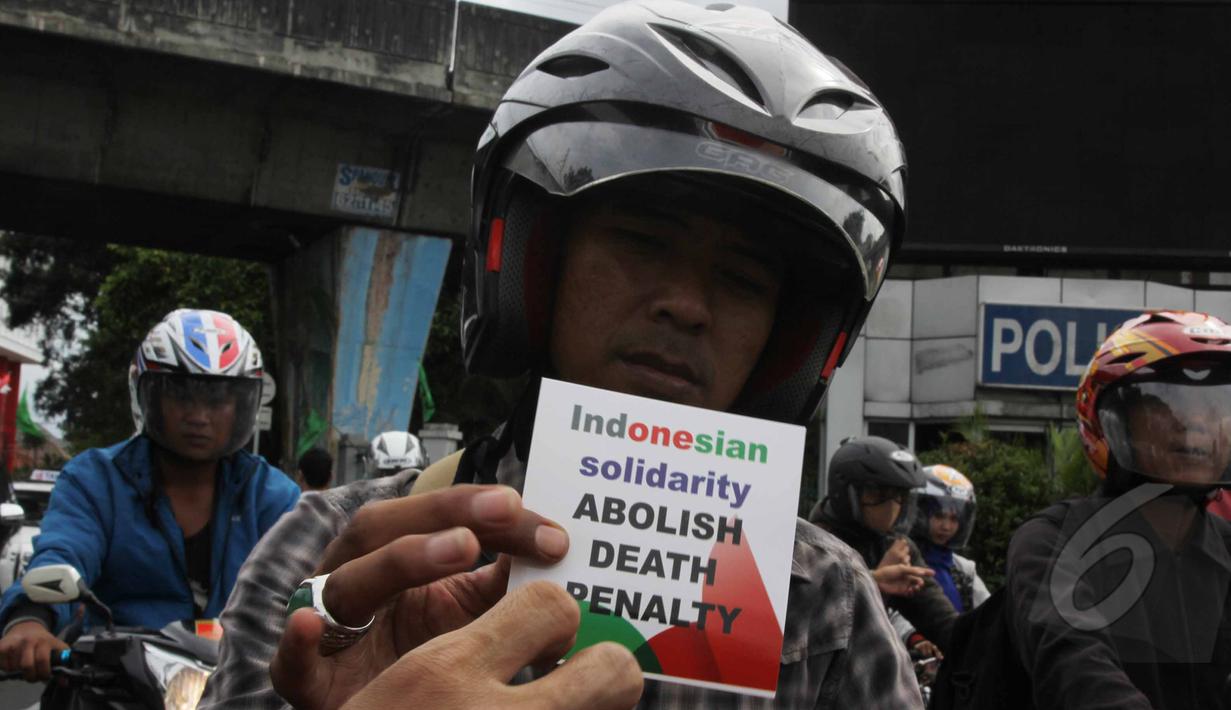 Seorang pengendara motor memperlihatkan stiker yang didapatnya saat aksi menolak hukuman mati di Megaria, Jakarta, Jumat, (24/4/2015). (Liputan6.com/Helmi Afandi)
