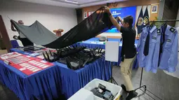 Mereka diringkus di kawasan Babakan Madang, Kabupaten Bogor, karena diduga menyalahgunakan izin tinggal dan diduga menjalankan praktik online scam atau penipuan daring. Tampak dalam foto, petugas Imigrasi menutupi barang bukti yang disita dari warga negara Jepang yang diduga terlibat dalam sindikat penipuan daring (online), di Bogor, Jawa Barat, Rabu 4 Maret 2026. (AP Photo/Achmad Ibrahim)