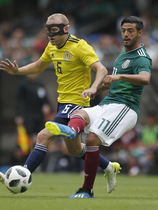 Pemain Skotlandia, Dylan McGeouch (kiri) berusaha mengganggu pemain Meksiko, Carlos Vela pada laga uji coba di Azteca Stadium, Meksiko City, (2/6/2018). Meksiko menang 1-0. (AP/Eduardo Verdugo)