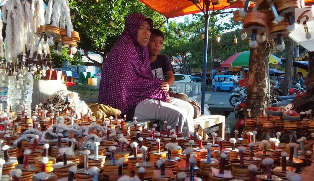 Pedagang menunggu pembeli saat berjualan pelita di Jalan Sam Ratulangi, Kota Gorontalo, Rabu (22/5/2019). Sejumlah pedagang menjual pelita dari botol bekas untuk menyambut perayaan Tumbilotohe atau malam pasang lampu yang digelar tiga hari menjelang Idul Fitri di Gorontalo. (Liputan6.com/Arfandi Ibr