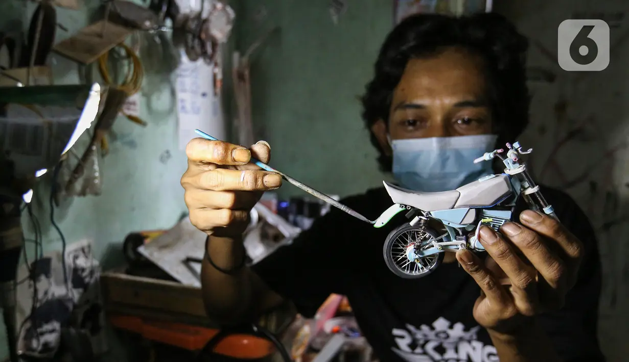 Pengrajin Wawang Kurniawan, mengecat miniatur motor RX-King di Kampung Dukuh, Serua, Tangerang Selatan, Sabtu (17/10/2020). Miniatur motor yang terbuat dari barang bekas paralon, kaleng minuman mulai digeluti sejak tahun 2018. (Liputan6.com/Fery Pradolo)