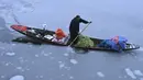 Seorang pria mengendarai sebuah kapal yang penuh dengan sayuran di dekat bagian beku danau Dal setelah hujan salju lebat di Srinagar (16/1/2020). Lapisan tipis es menutupi perairan Danau Dal di Srinagar. (AFP Photo/Tauseef Mustafa)