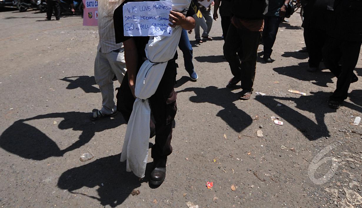 Massa menunjukkan kertas bertuliskan "We Love Indonesia" dan "Save Indonesia Generation from Criminal Drugs!" saat menggelar aksi  di depan pintu masuk Dermaga Wijaya Pura, Cilacap, Jateng, Jumat (6/3). (Liputan6.com/Johan Tallo)