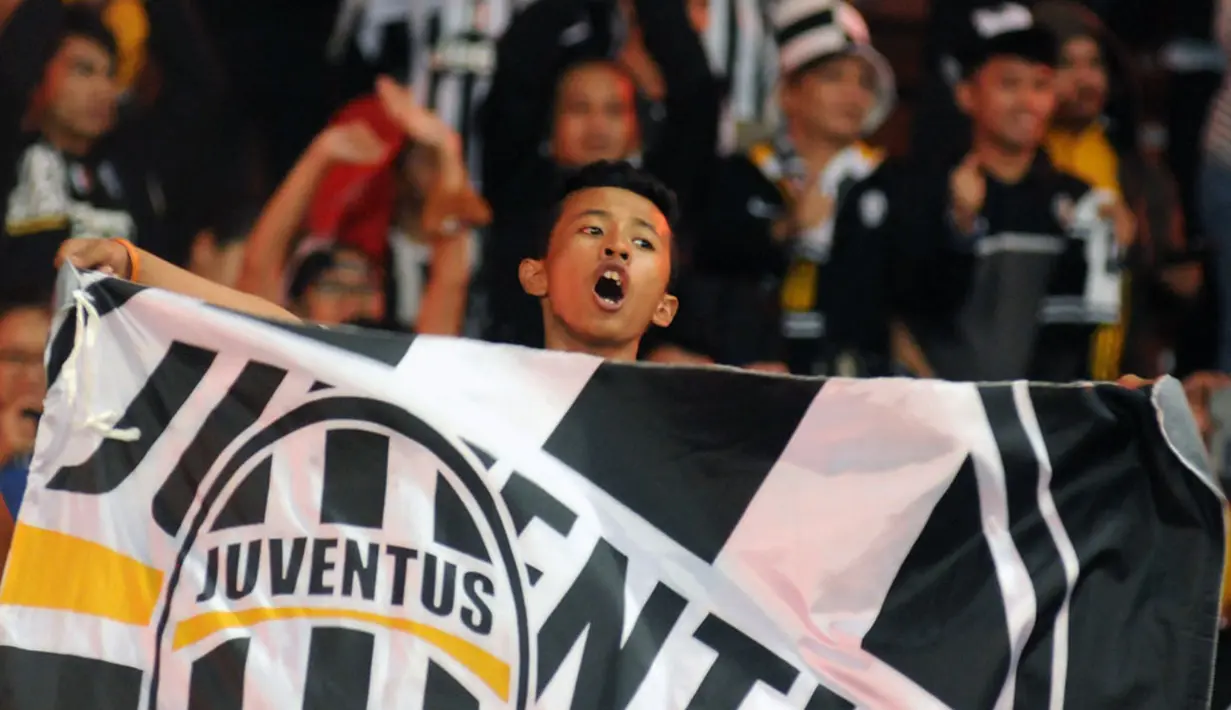 Sambil membentangkan bendera, salah satu suporter Juventus bernyanyi merayakan kemenangan I Bianconeri atas ISL All Stars 8-1 di Stadion GBK, Jakarta, (6/8/2014). (Liputan6.com/Helmi Fithriansyah)