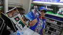 Seorang karyawati menunjukan kemasan rokok yang telah berganti peringatan bergambar di minimarket, Jakarta, Selasa (24/6/14). (Liputan6.com/Johan Tallo)