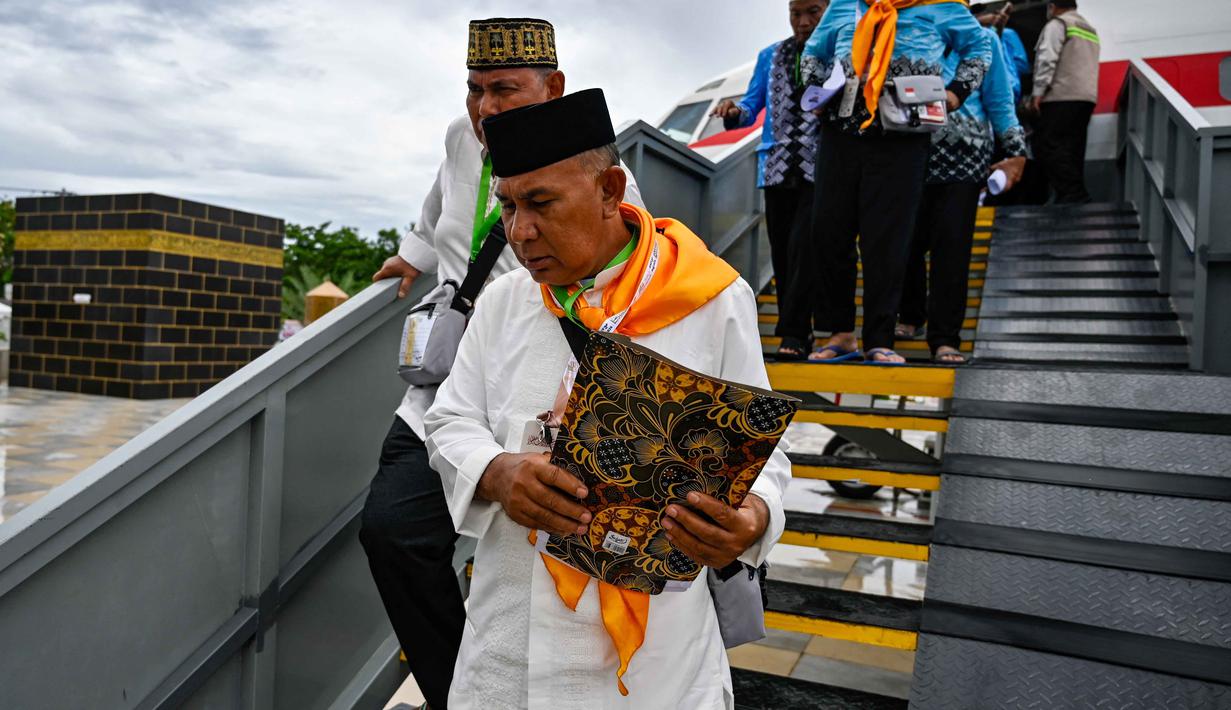 Para calon jemaah haji Indonesia turun dari pesawat Boeing 737 yang sudah tidak digunakan lagi selama sesi pelatihan keselamatan pra-keberangkatan di pusat embarkasi haji Banda Aceh pada Kamis 14 Mei 2026. (CHAIDEER MAHYUDDIN/AFP)