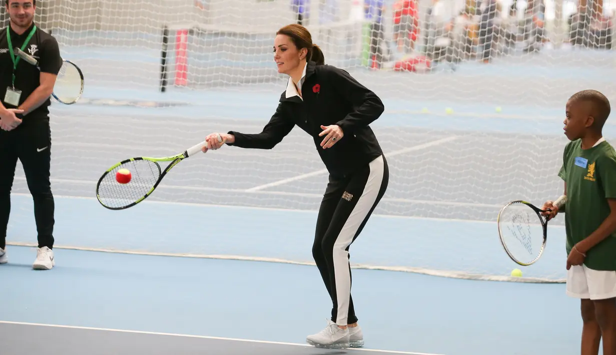 Kate Middleton berlatih main tenis saat mengunjungi Lawn Tennis Association di Pusat Tenis Nasional, London, Senin (31/10). Tak hanya berolahraga, Kate juga mendorong anak-anak usia 5-8 tahun, supaya menggemari olahraga itu. (Daniel LEAL-OLIVAS/POOL/AFP)