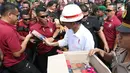 Presiden Joko Widodo atau Jokowi saat membagikan buku dan kain batik kepada warga sekitar Bandara Soetta, Tangerang, Banten, Kamis (21/6). Bagi-bagi buku tersebut merupakan rutinitas Jokowi usai blusukan. (Liputan6.com/Angga Yuniar)