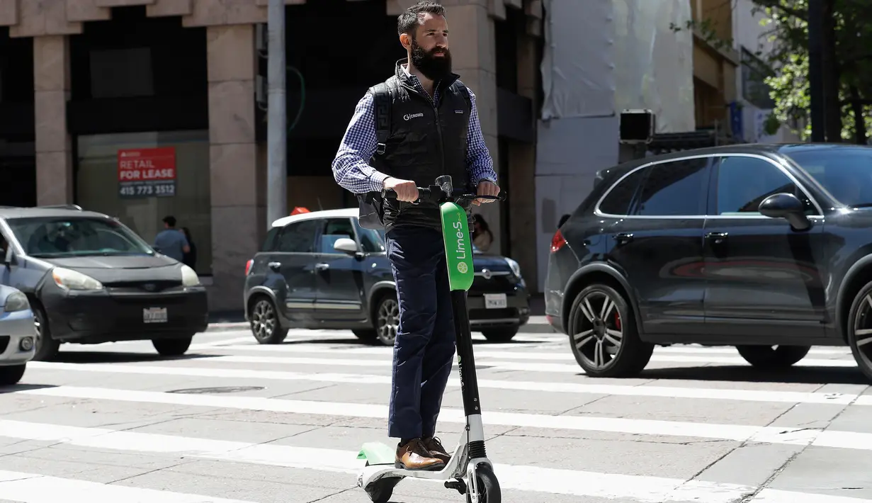 Seorang pria mengendarai skuter bermotor di jalanan di San Francisco (17/4). Pemberhentian operasi skuter bermotor ini karena belum adanya kepastian terhadap keamanan dan keselamatan penggunaan skuter di tempat umum. (AP/Jeff Chiu)