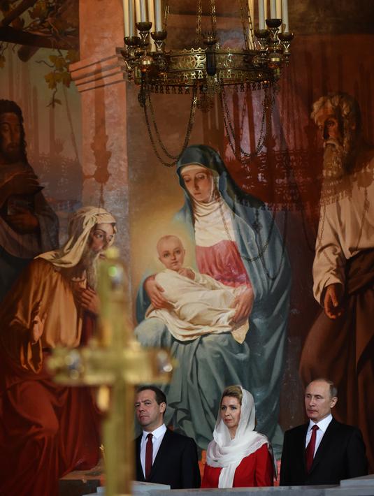 Presiden Rusia Vladimir Putin (kanan) bersama Perdana Menteri Rusia Dmitry Medvedev (kiri) dan istrinya Svetlana saat menjalani prosesi Paskah Ortodoks di Gereja Katedral Kristus Juru Selamat di Moskow, Rusia,(16/4). (AFP Photo / Vasily Maximov)