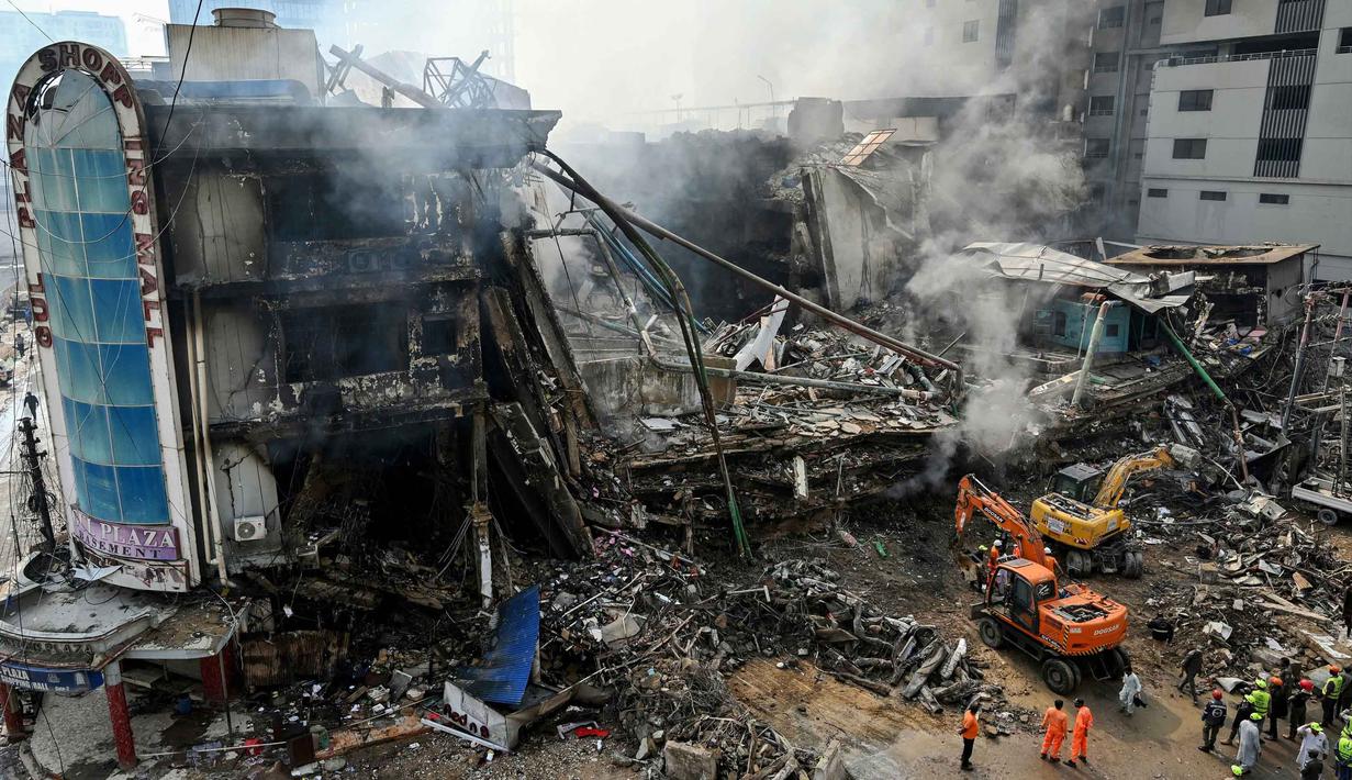 Petugas penyelamat mencari korban di antara puing-puing setelah kebakaran besar di sebuah pusat perbelanjaan di Karachi pada Senin 19 Januari 2026. Tim pencari dan penyelamat di Karachi, Pakistan, masih berjuang melakukan pencarian korban di reruntuhan sebuah gedung pusat perbelanjaan. (Asif HASSAN/AFP)